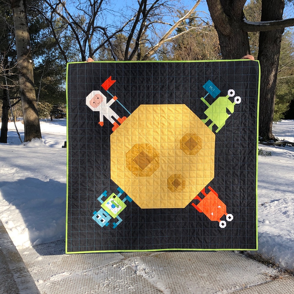 Apples & Beavers Party Planet baby quilt on snowy driveway