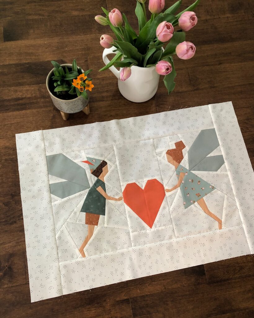 Apples and Beavers, Fairies and heart mini quilt tutorial - completed quilt top on hardwood floor, a vase with tulips in the background
